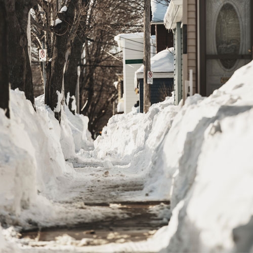 人行道已被清理干净，但仍有零星积雪，积雪深度达几英寸。