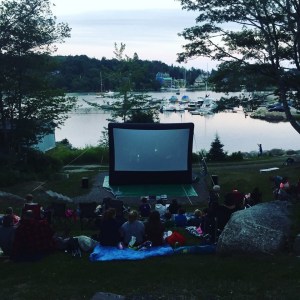 人们在哈伯兹的户外屏幕上观看电影，背景是帆船。