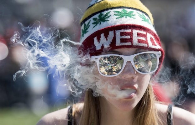 A photo of a woman smoking pot while wearing a hat that says 