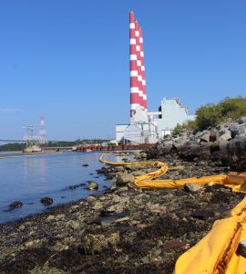 图中是塔夫茨湾发电厂附近海岸线上的围油栏