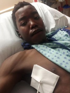 一张年轻黑人男子在医院的病床上用绷带包扎伤口的照片