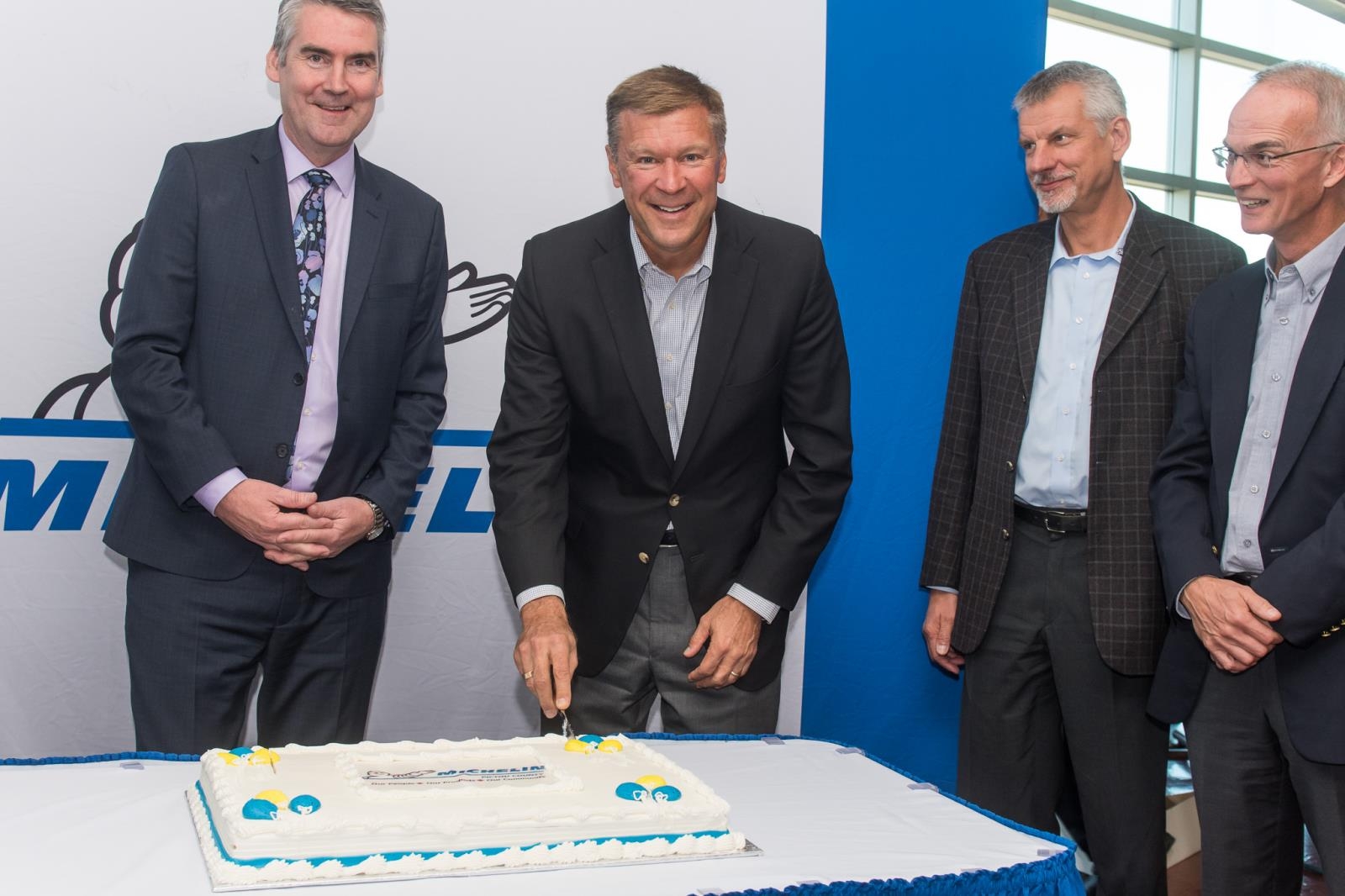 四个穿西装的白人切了一个大蛋糕。