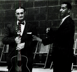 两个人在舞台上表演的黑白照片。左边的男人拿着一把吉他。