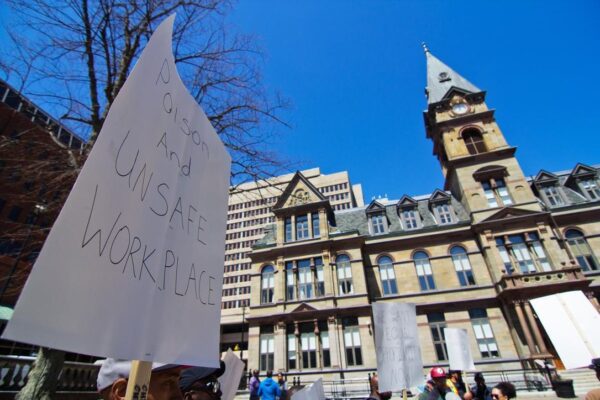 在阳光明媚的日子里，市政厅前有一个写着有毒和不安全工作场所的标志。