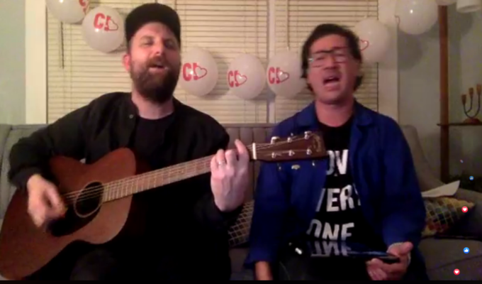 两个人一起唱歌，一个拿着吉他