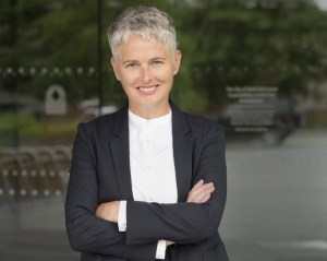 Aoife MacNamara博士的照片。她留着灰色的短发，抱着双臂对着镜头微笑。她穿着深灰色西装和白色衬衫。