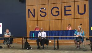 人们在NSGEU标志下的桌子中的社会距离