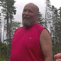 Smiling man in a red muscle shirt outdoors.