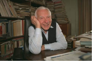 在办公桌微笑的人在他身后的书架。