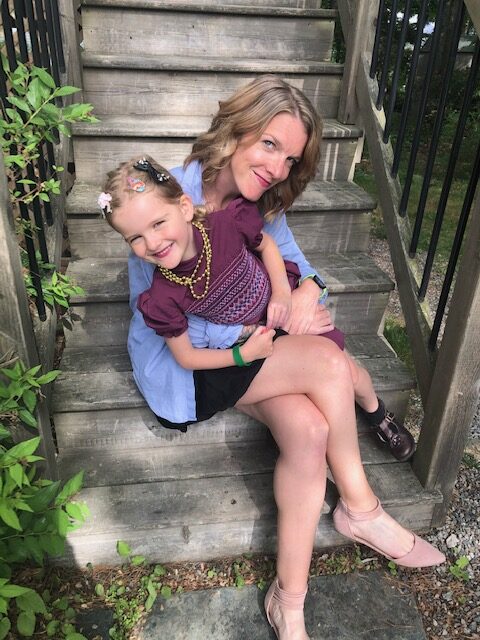 Smiling woman sitting on steps holding a smiling child.