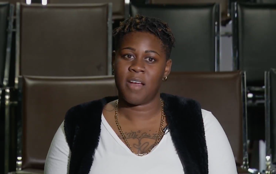 穿着白色v领衬衫和黑色背心的黑人妇女看着摄像机