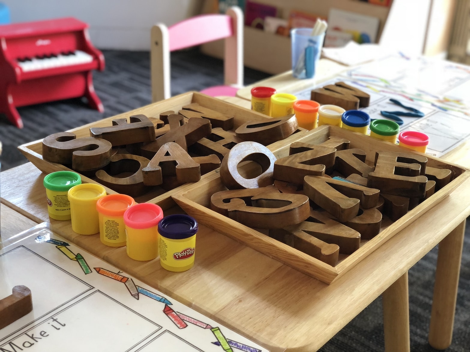 Wooden letters and play-doh on an elementary classroom desk.