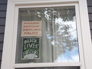 窗户上有两个标志:“解除武装，撤资，废除警察”和“黑人的生命也重要”