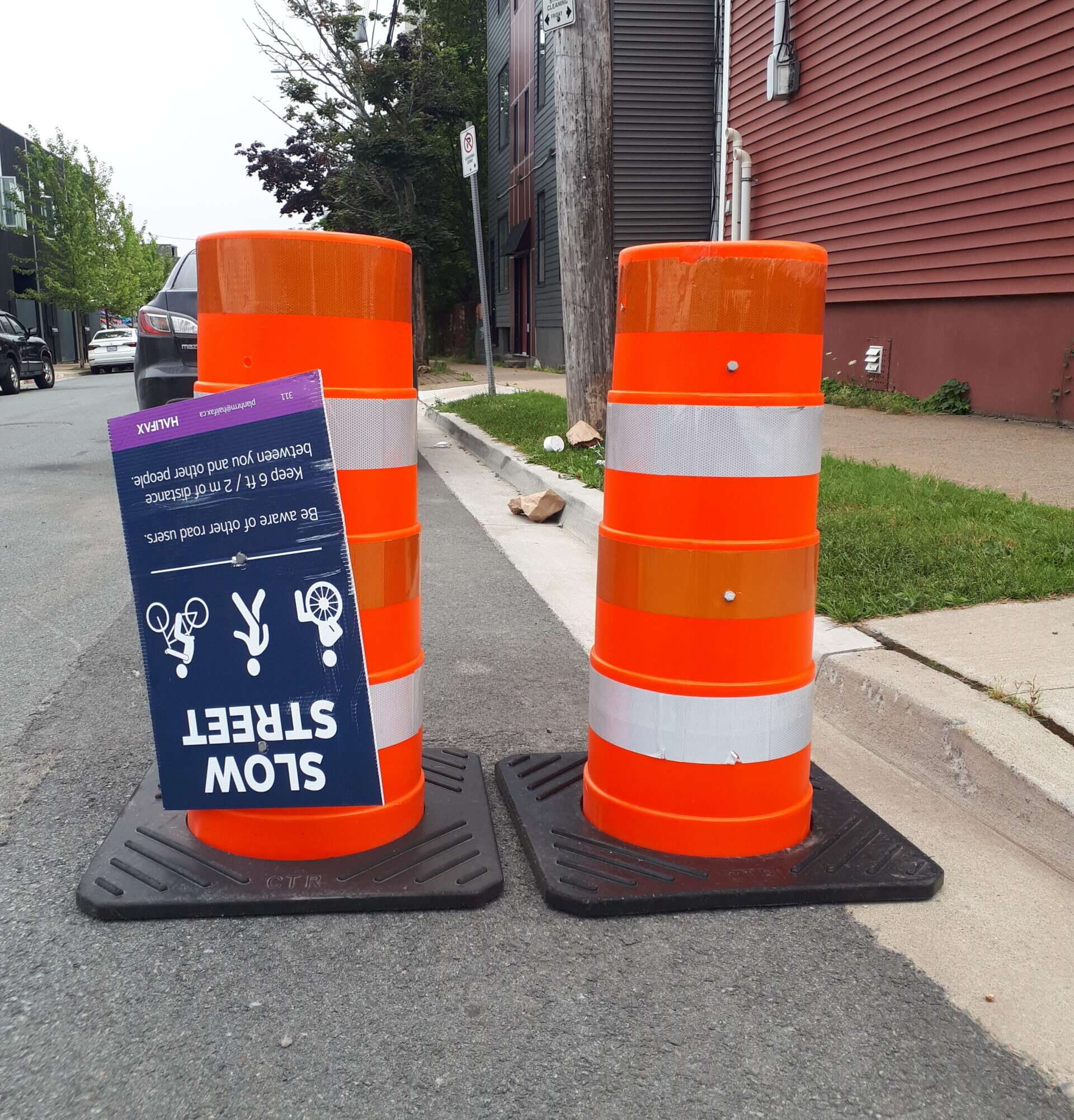 路边有两个交通锥，还有一个上下颠倒的“慢路”标志