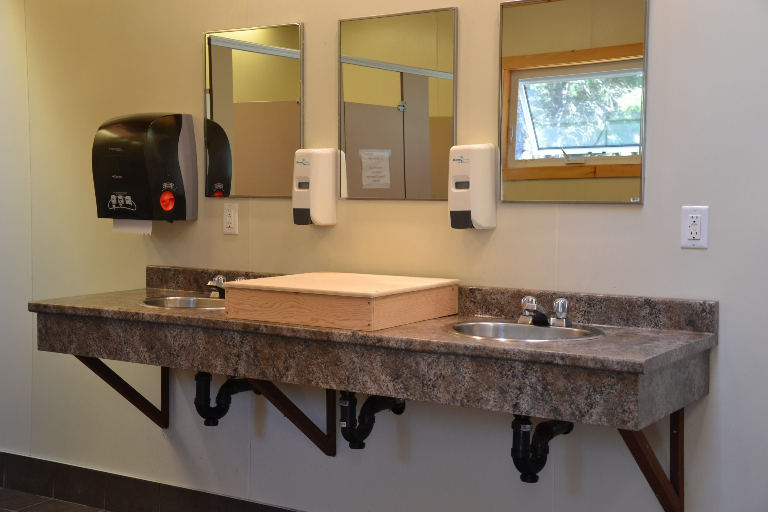 有三个盥洗室的公共浴室，其中一个被堵住了。