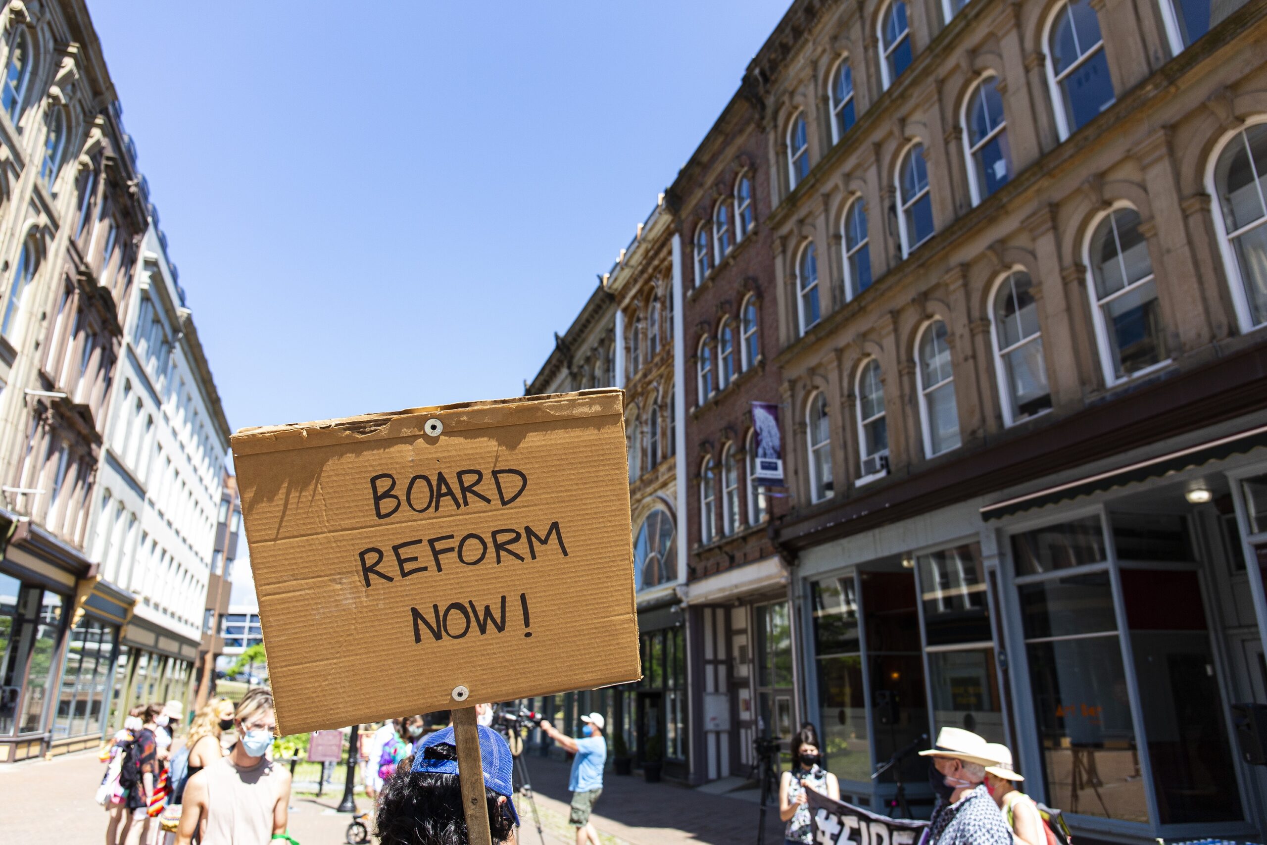 一张人们在格兰维尔购物中心聚会的照片，一张写着“董事会改革!”