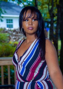 甲板的少妇有箍耳环的和镶边礼服，与在她的面孔的沉思看看。