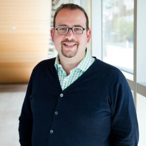 有山羊胡子和羊毛衫的微笑的人在窗口前面。