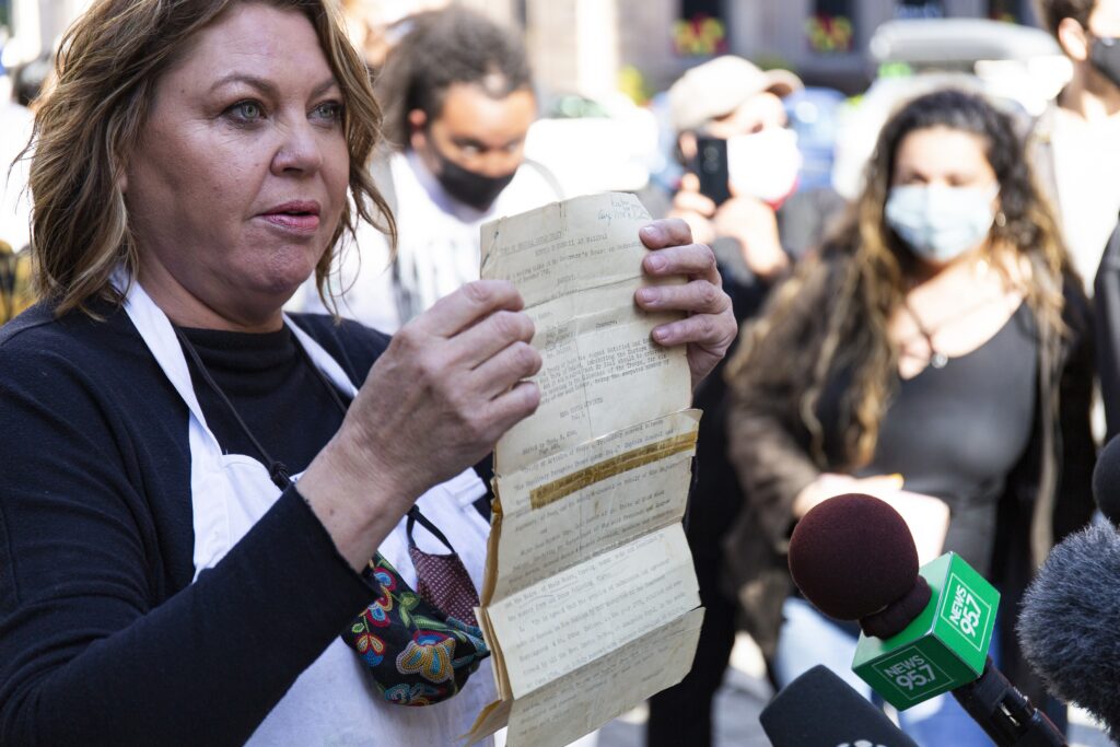 2020年10月16日，周五，谢丽尔·马洛尼(Cheryl Maloney)在哈利法克斯省议会大厦前举起她阿姨的《1752年条约》副本。-图片:Zane Woodford