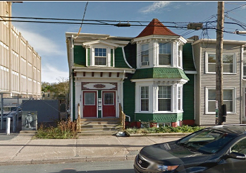 一座绿色的两层楼房，前面有一扇凸窗，白色装饰。