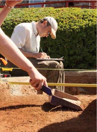 一个穿着白衬衫戴着帽子的人在考古挖掘现场。