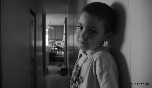 一个孩子靠在墙上的黑白照片。