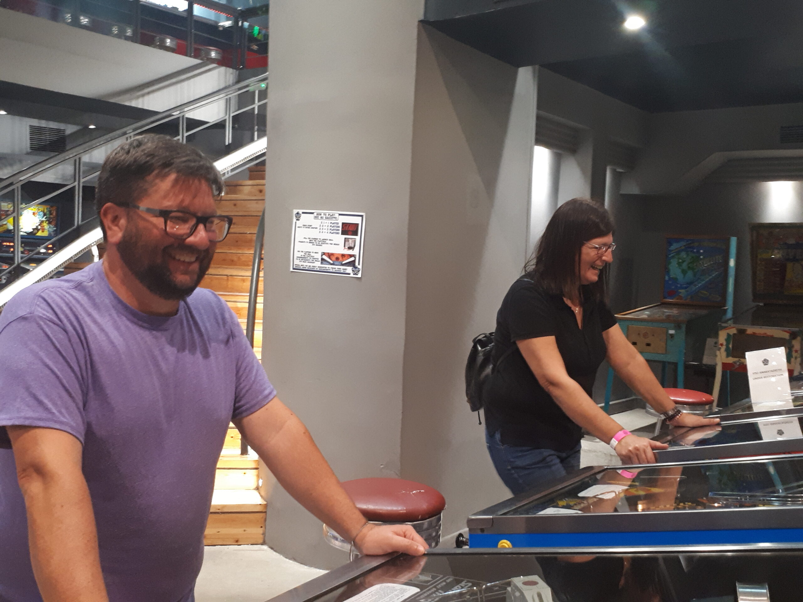 一男一女在两台不同的弹球机上玩。