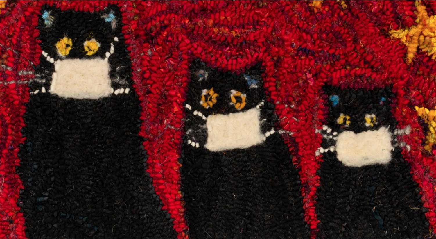 这是劳拉·肯尼制作的钩状地毯的照片。有三只长着黄色眼睛的黑猫，每只都戴着白色的面具。背景是不同的红色漩涡，还有明亮的黄色和橙色星星。这可以说是哈利法克斯考官网站上最明亮的图像。