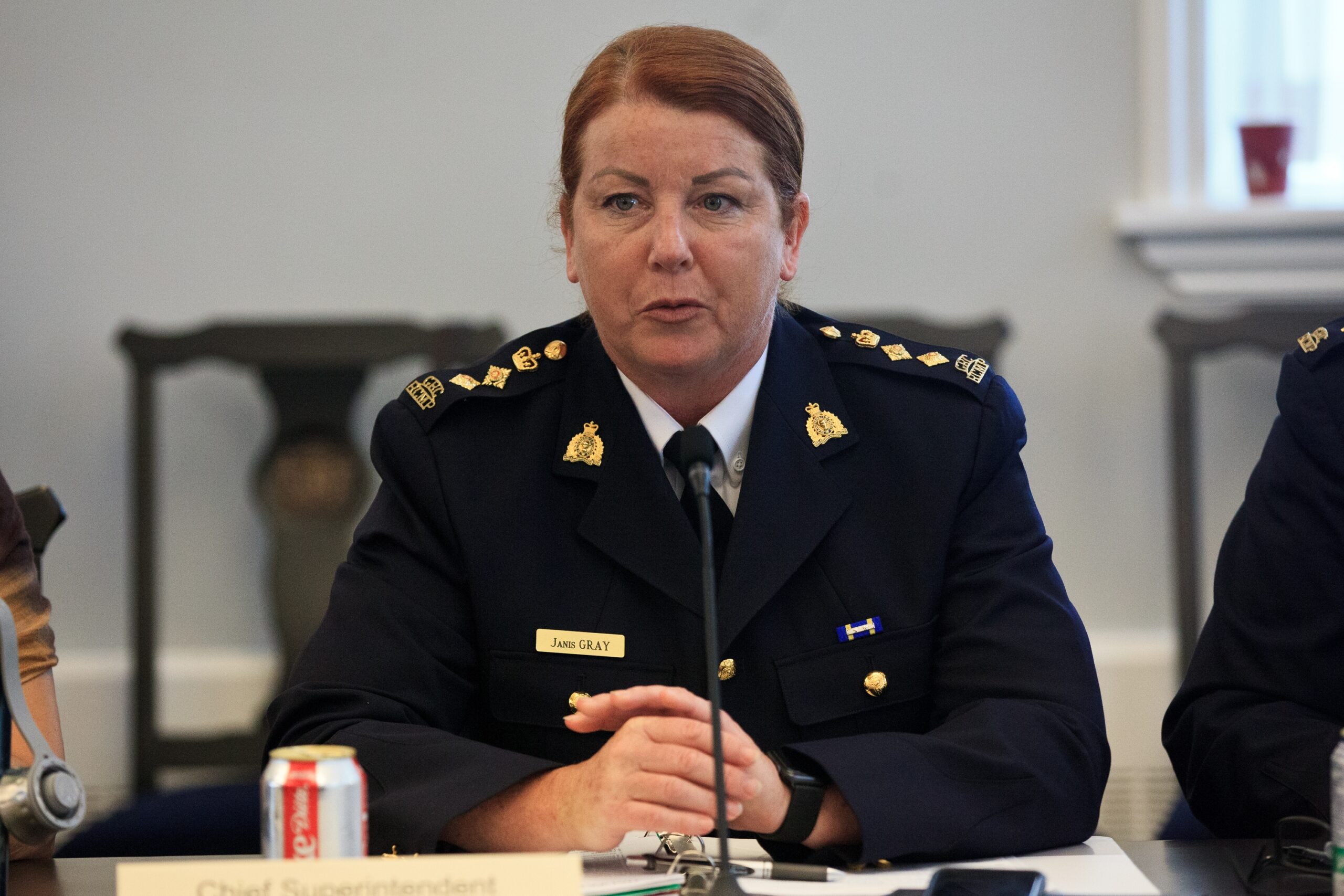一位身穿黑色制服的中年白人妇女坐在麦克风前