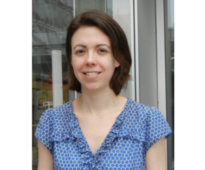 Karina Top博士is a white woman with chin-length brown hair. She's wearing a pale blue patterned blouse with a ruffle trim.