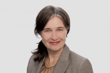 一名扎着齐肩马尾辫、穿着商务夹克、看着镜头的女性的头像。