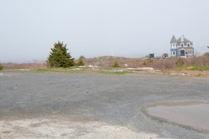 砾石停车场，背景是常青树和蓝色房子。