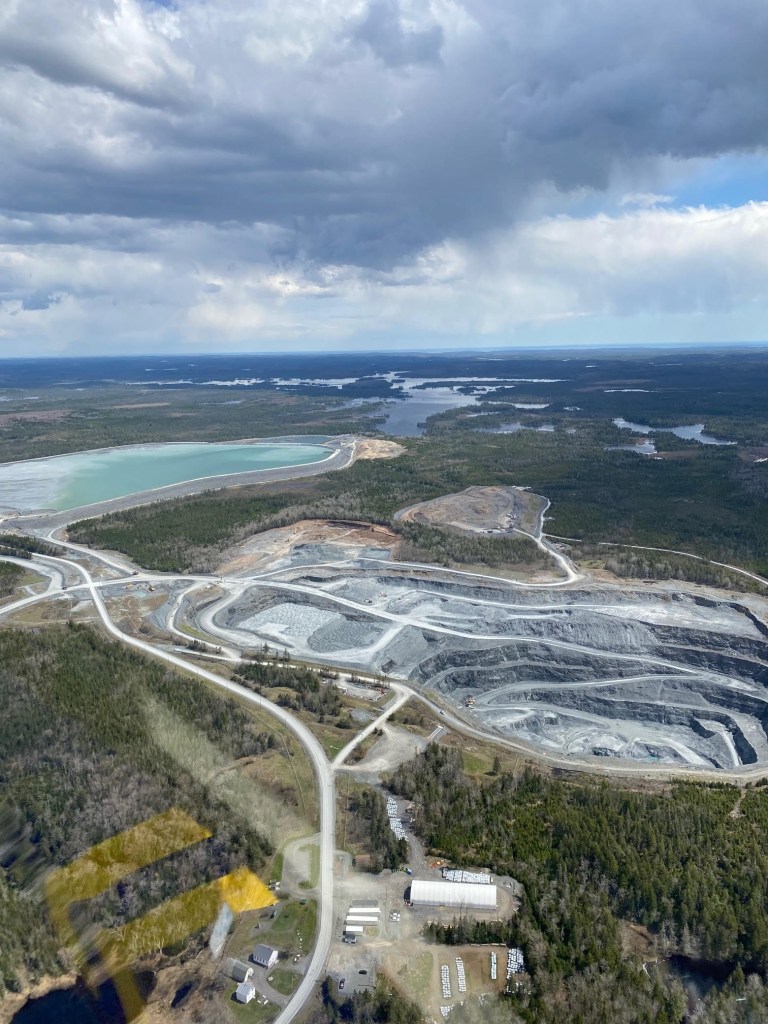 这张大西洋黄金公司在Moose河的Touquoy露天金矿的航拍照片显示了金矿开采的巨大陨石坑，以及位于Scraggy湖边缘的大型尾矿库。照片是贡献。