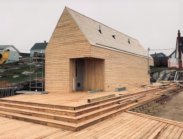 一个小型的框架木结构的照片，它将成为佩吉湾的洗手间。有一个很大的木制甲板，有三个台阶通向上层甲板，但还没有看到坡道。