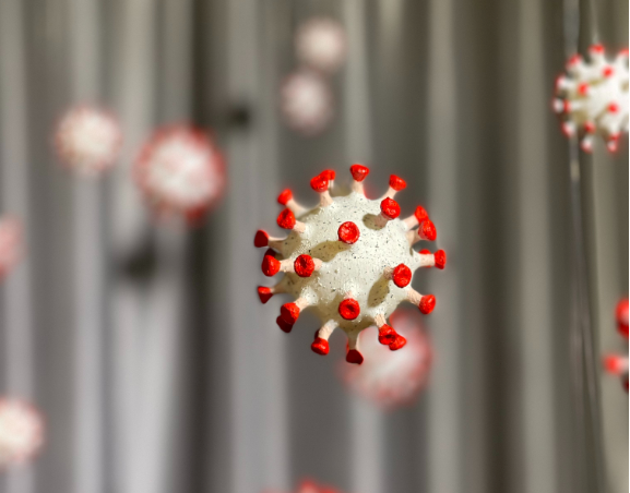 冠状病毒雕塑的照片，在似乎是纸质机械的东西中制作的。这是米色的红色冠，并悬挂中空，悬挂在背景中的副本，焦点。