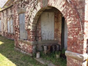一幅展示建筑拱形门廊细节的照片。砖被风化了，xome已经碎裂了。看起来红砖可能曾一度被刷成白色，但大部分已经磨损殆尽。