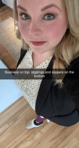 一张年轻的金发女子的照片，她穿着一件黑色运动夹克，带点的衬衫，酒红色运动裤和舒适的拖鞋。