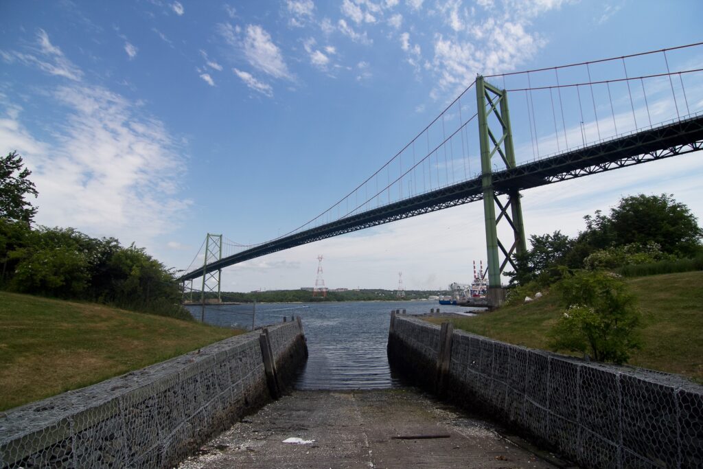 A. Murray Mackay桥在2018年的一个阳光灿烂的夏日，面向东方的照片，俯视船只，沿着跨越船。在远处，您可以看到红色和白色堆栈的Tufts Cove。