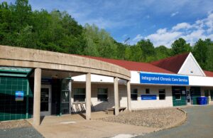 长期综合护理服务大楼入口的照片，后面是绿树和蓝色的夏日天空。