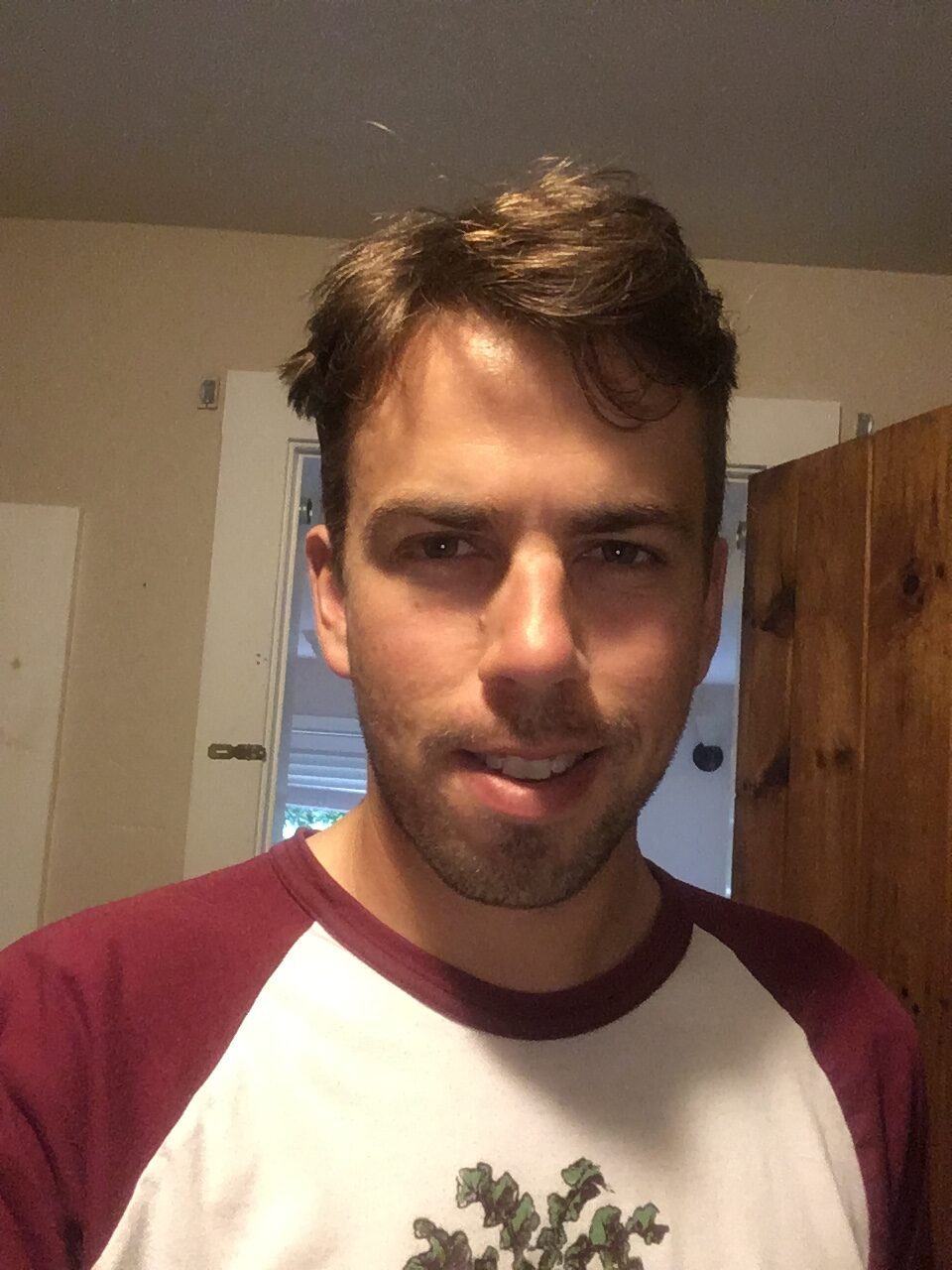 伊森拍了一张自拍。他是个英俊的年轻人，面带腼腆的微笑，穿着一件白色棒球衫，袖子是酒红色的，上面看起来像是蓟的图案。他的棕色头发刚剪完，他需要修面。