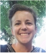 艾伦摩尔照片，可能是一个selfie，在一个明亮的夏日微笑与树和天空的照相机。