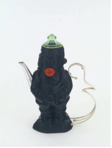 Leopold foulem的“黑色圣诞老人咖啡壶”。这是一个坚实的黑色陶瓷圣诞老人，脾气暴躁，巧妙的亮红色嘴唇。喷口和手柄由银金属制成，盖子似乎是绿色玻璃。