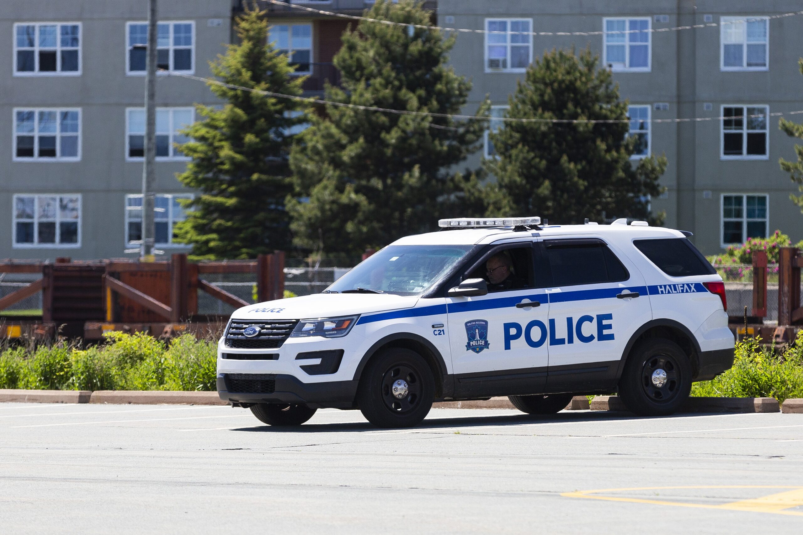 2021年6月，一个阳光明媚的日子，哈利法克斯地区警察在他们的巡逻车里。它停在一个停车场里，“POLICE”的大写字母与那闪闪发光的白色油漆形成鲜明的对比。透过有色玻璃你几乎看不到警察，但看起来他们在看手机。也许他们在吃午饭。