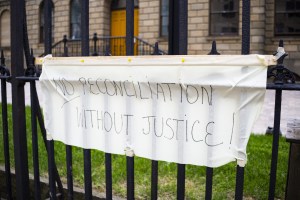 2021年6月，白色织物上用黑色马克笔写着“没有正义就没有和解”的牌子挂在省府大门上。-图片:Zane Woodford