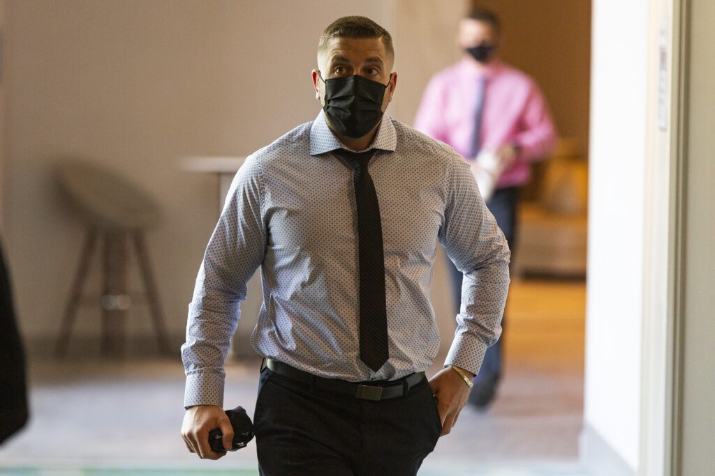 一名身穿黑白圆点衬衫、打着黑色领带、戴着黑色面具的男子走在酒店的走廊上。