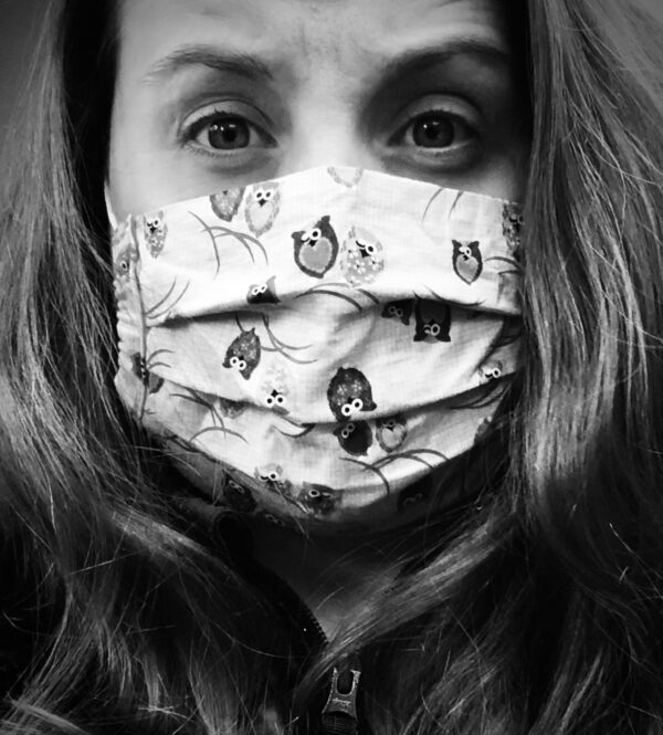 詹妮弗·蒙特的黑白照片。她长长的黑发衬托出她愁容满面。她戴着一个印有猫头鹰卡通图案的浅色织物面具。