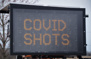 室外电子标志读了在黑暗的背景的黄色大写字母的covid射击。