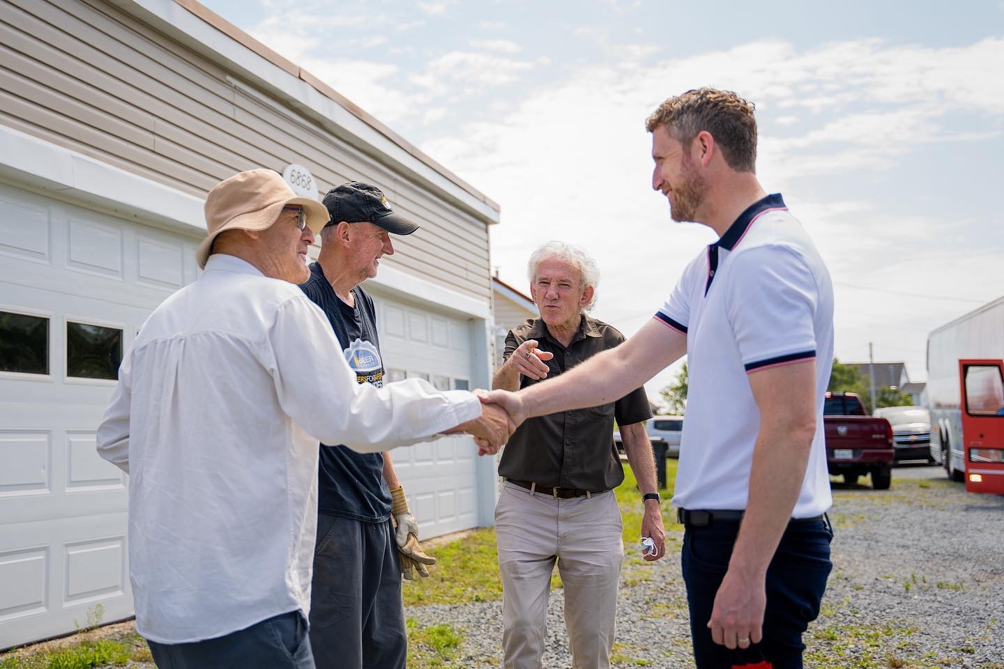 伊恩·兰金（Iain Rankin）没有戴面具，他和一个没有戴面具的男人握手，另外两个没有戴面具的男人站在旁边，其中一个指着他们紧握的手。