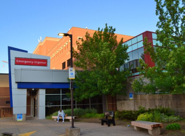 一名妇女坐在哈利法克斯医院急诊科门前的长凳上。