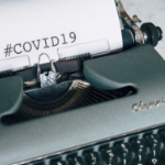 一个绿色打字机，与短语covid 19打字在白皮书上